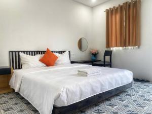 a bedroom with a large white bed with orange pillows at SAKURA Retreat in Mộc Châu