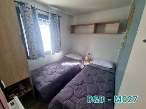 a bedroom with two beds and a window at Camping les dunes Torreilles Plages - Bungalow M027 chez D&D in Torreilles