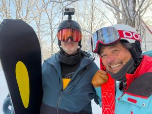 two men wearing helmets standing next to a snowboard at Tesoro Okushiga in Yamanouchi
