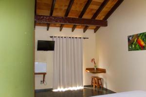 リオ・ヴェルデ・デ・マット・グロッソにあるHotel Serra Verdeのベッドルーム(ベッド1台、白いカーテン付)