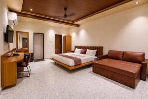 a bedroom with a bed and a couch and a desk at The Crystal Woods Resort in Mendarda