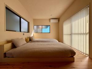 a bedroom with a large bed with two windows at Beppu TOJIHAUS 001 2min walk to Shibaseki Onsen in Beppu