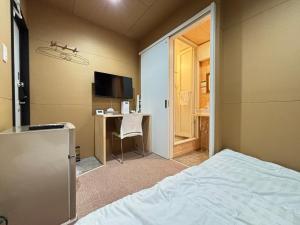 a bedroom with a bed and a desk and a television at NikkaHotel東郷店 in Togo