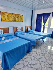 three beds in a room with blue sheets at Hotel Tagudan Kubo Corporation in Tagudin +120 photos
