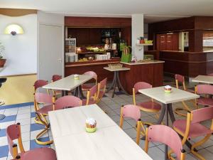 a restaurant with white tables and pink chairs at ibis budget Nuits Saint Georges in Nuits-Saint-Georges