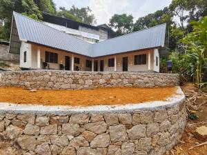 a house with a stone wall in front of it at Riverwood Cottages in Kallar Vattiyar