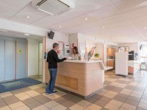 a man and a woman standing at a counter at ibis budget Amberieu en Bugey/Chateau Gaillard A42 in Château-Gaillard