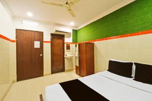 a bedroom with a bed with a green wall at Super Hotel O MAK RESIDENCE in Shamshabad +27 photos