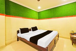 a bedroom with a bed with green and orange stripes at Super Hotel O MAK RESIDENCE in Shamshabad