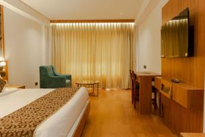 a hotel room with a bed and a chair at Hotel Sky International in Kizhake Chālakudi