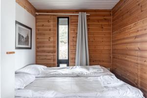 a bed in a room with a wooden wall at Himos Mökki in Jämsä