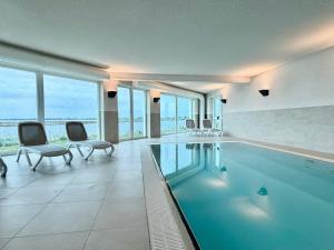 a swimming pool in a building with chairs and windows at Ostseeblick-Bollwark Whg 9 in Olpenitz