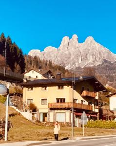 a woman standing in front of a building with a mountain at Primiero Suite 3 downtown, garden in Transacqua