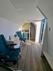 a living room with blue chairs and a table and a kitchen at The Orkney Pod in Stromness