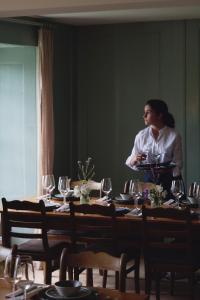 a woman standing behind a table with wine glasses at Hotel St Petersinsel in Sankt Petersinsel