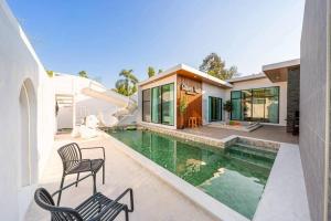 a house with a swimming pool and two chairs at Silver Hill Pool Villa Pattaya in Na Jomtien