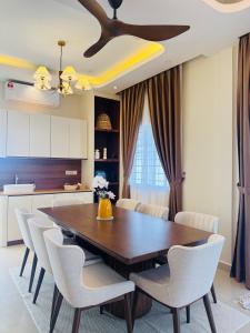 a dining room with a wooden table and white chairs at Bayu Senja in Lahad Datu