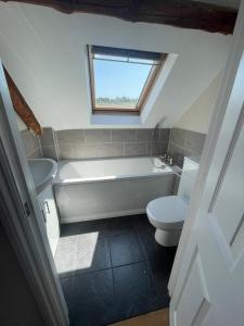 a bathroom with a tub and a toilet and a window at Copswood Cottage in Stroud