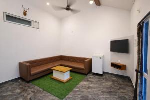 a living room with a brown couch and a table at The Crystal Woods Resort in Mendarda +12 photos