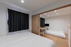 a bedroom with a white bed and a desk at HARUSAKU Omachi in Asahikawa