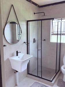 a bathroom with a sink and a shower with a mirror at 38 stay in eMalahleni