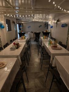a dining room with long tables and chairs and lights at Apartman SOKAK in Satnica