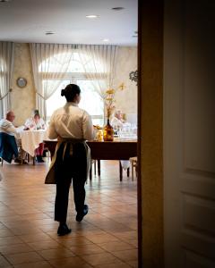 a woman standing at a table in a restaurant at Logis Hôtel & Restaurant Le Cheval Blanc et Clovis in Vouillé