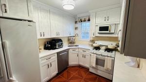 a white kitchen with white cabinets and a refrigerator at Casseus J Legacy in Rosedale