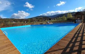 a swimming pool with blue water and mountains in the background at Dom pod Mandragorą in Świeradów-Zdrój
