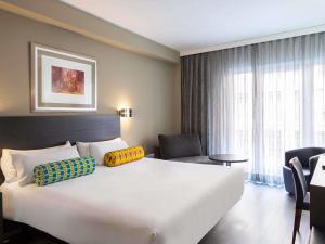 a hotel room with a large white bed and a large window at Mercure Madrid Centro in Madrid +90 photos
