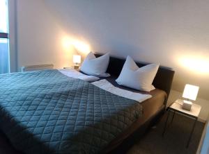 a bedroom with a bed with white pillows and two lamps at Fischstübchen Neeberg Fewo 2 - Achterwasser in Krummin