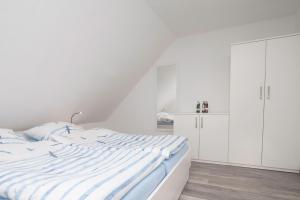 a white bedroom with a bed and white cabinets at Ferienhaus Lükko in Greetsiel