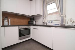 a white kitchen with white cabinets and a window at Ferienhaus Lükko in Greetsiel