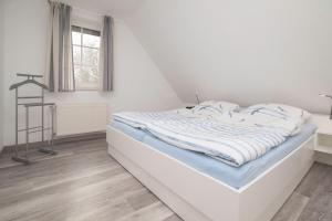 a bed in a white room with a window at Ferienhaus Lükko in Greetsiel