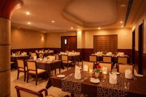 a restaurant with tables and chairs in a room at Hotel Indraprastha Thiruvalla in Talavadi