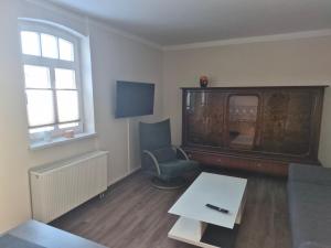 a living room with a table and a chair and a tv at Alter Kräutergarten in Dabel