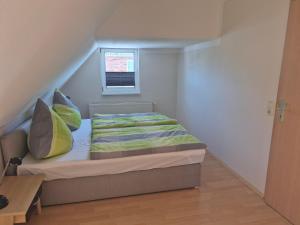 a small bedroom with a bed with pillows and a window at Alter Kräutergarten in Dabel
