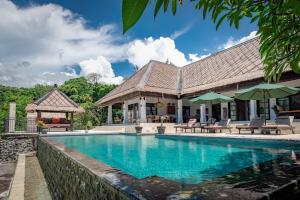a villa with a swimming pool and a house at Villa Bayu - exclusive villa with infinity pool, wellness pavilion, panoramic ocean view & full service in Temukus