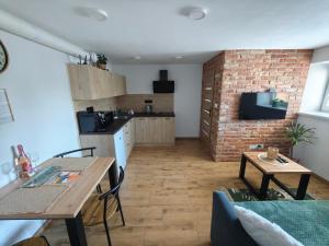 a living room with a table and a kitchen with a brick wall at Apartmán BASARIJA in Hrabušice