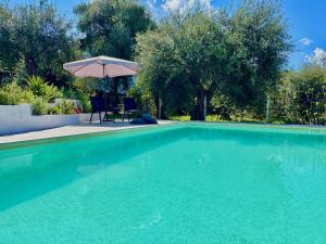 a swimming pool with a table and an umbrella at Elea Boutique Villa with private pool by DadoVillas in Acharavi +28 photos