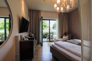 a bedroom with a mirror and a bed and a chair at Seeside Hotel SEEWIRT MATTSEE in Mattsee +30 photos