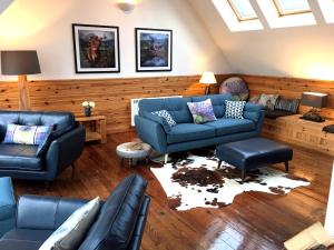 - un salon avec des canapés bleus et un canapé dans l'établissement Windyhill Cottage, à Achiltibuie