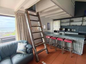 a living room with a bar with a ladder and stools at Sandkasteel Self-Catering Accommodation in Vosburg
