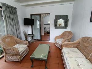 a living room with wicker chairs and a couch at Sandkasteel Self-Catering Accommodation in Vosburg