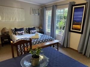 a bedroom with a bed and a table and windows at Tranquility Town Stays in Winterton
