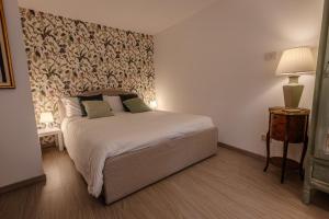 a bedroom with a white bed with a floral wallpaper at Maison Orange - Dimora nelle Langhe in Neive