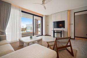 a living room with a couch and a table and a tv at Angsana Oceanview Residences Building 2 in Laguna by Banyan Living in Bang Tao Beach