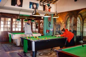 two men playing billiard in a room with pool tables at Hotel VATOLA in Antsirabe