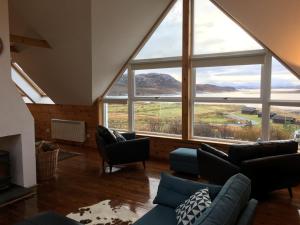 ein Wohnzimmer mit großen Fenstern und einem Sofa in der Unterkunft Windyhill Cottage in Achiltibuie