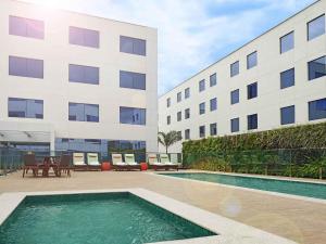 a building with a swimming pool in front of a building at Novotel Rio de Janeiro Parque Olimpico in Rio de Janeiro